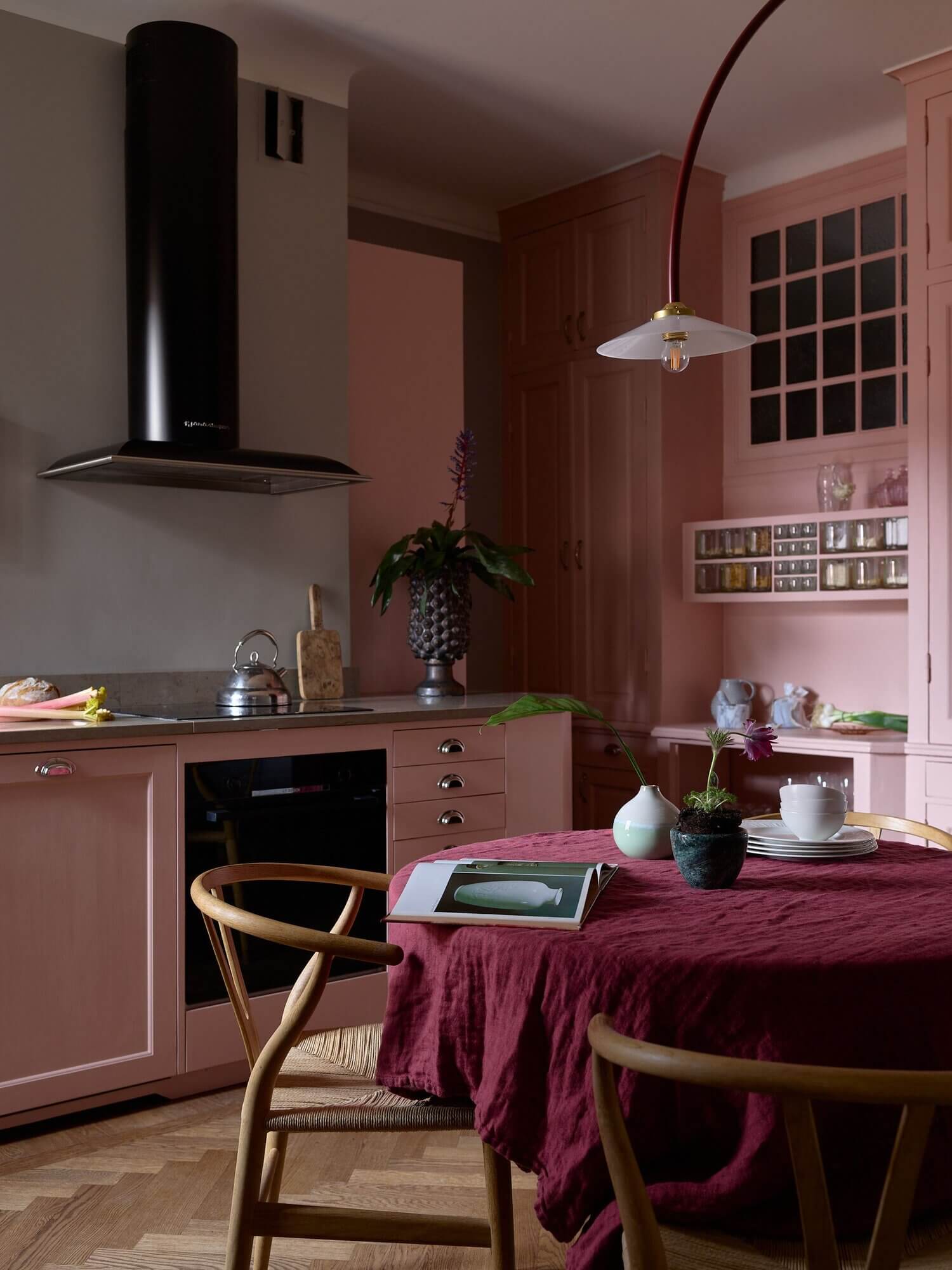 A Viva Magenta tablecloth anchors a deep richness with the lighter pink cabinetry.