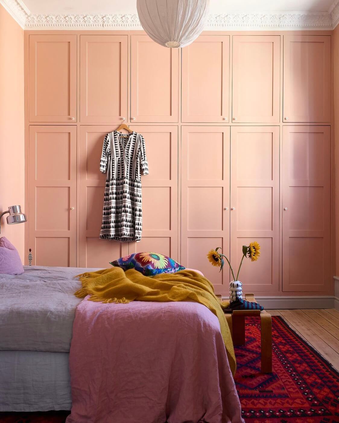 This pink bedroom in a colorful family home combined a plaster pink shade with a bold Viva Magenta rug.