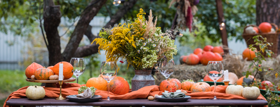 Fall themed holiday table setting arrangement for a seasonal party, banner Thanksgiving outside
